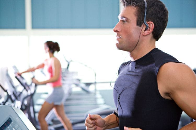 man with headphones on running on treadmill at the gym