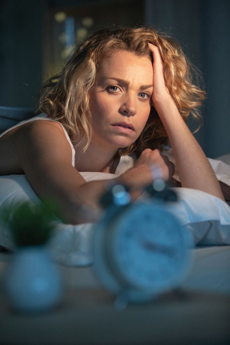 tired woman looking at camera from bed