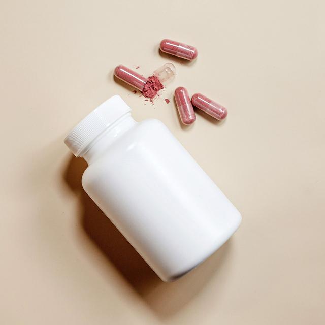 white pill bottle with capsules beside it